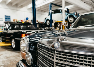 Close-up of the iconic Mercedes-Benz emblem on a restored classic model in the Miami Benz workshop.